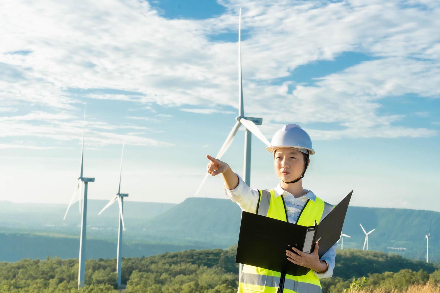 mulheres engenheiras trabalhando e segurando o relatório na estação de gerador de energia de turbina eólica na montanha, tailândia foto