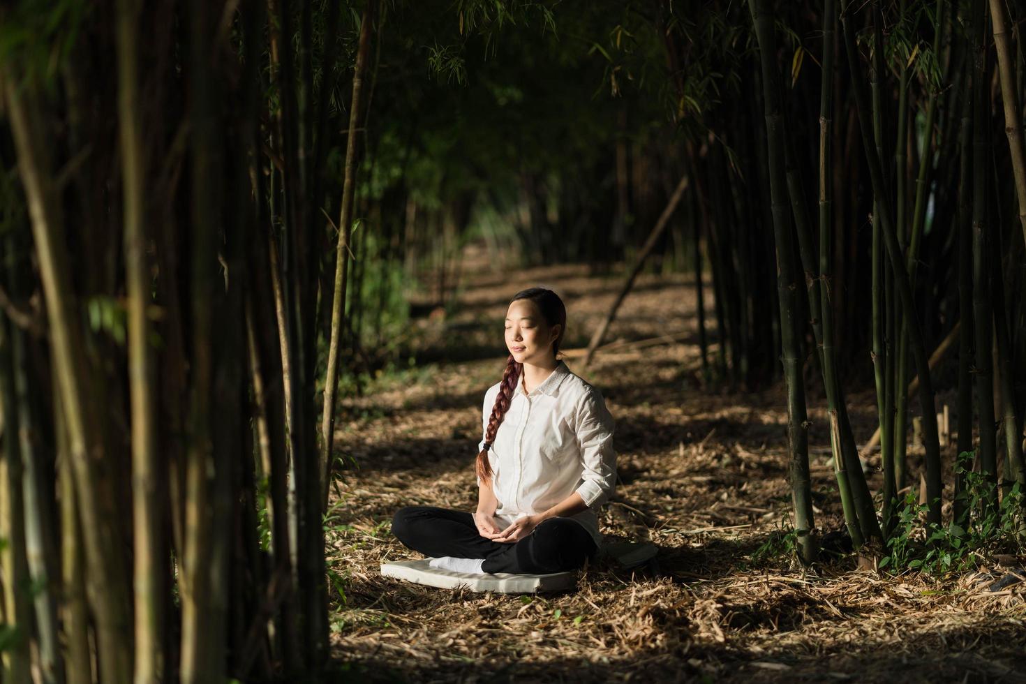 linda mulher meditando na floresta de bambu foto