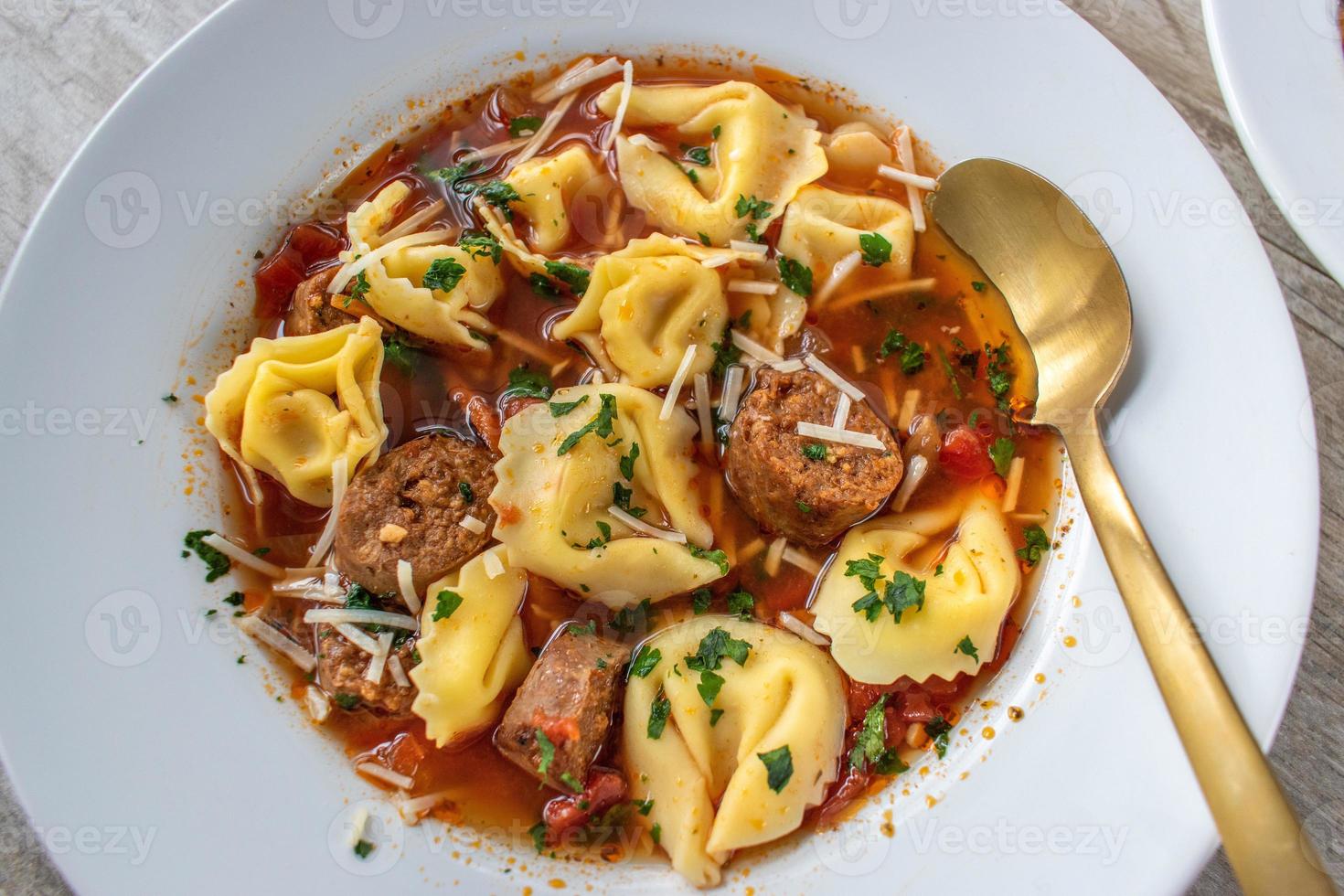 tigela de sopa de tortellini com salsicha italiana plana lay foto