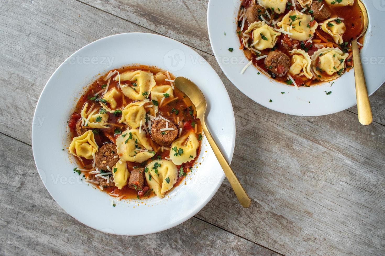 tigela de sopa de tortellini com salsicha italiana plana lay foto