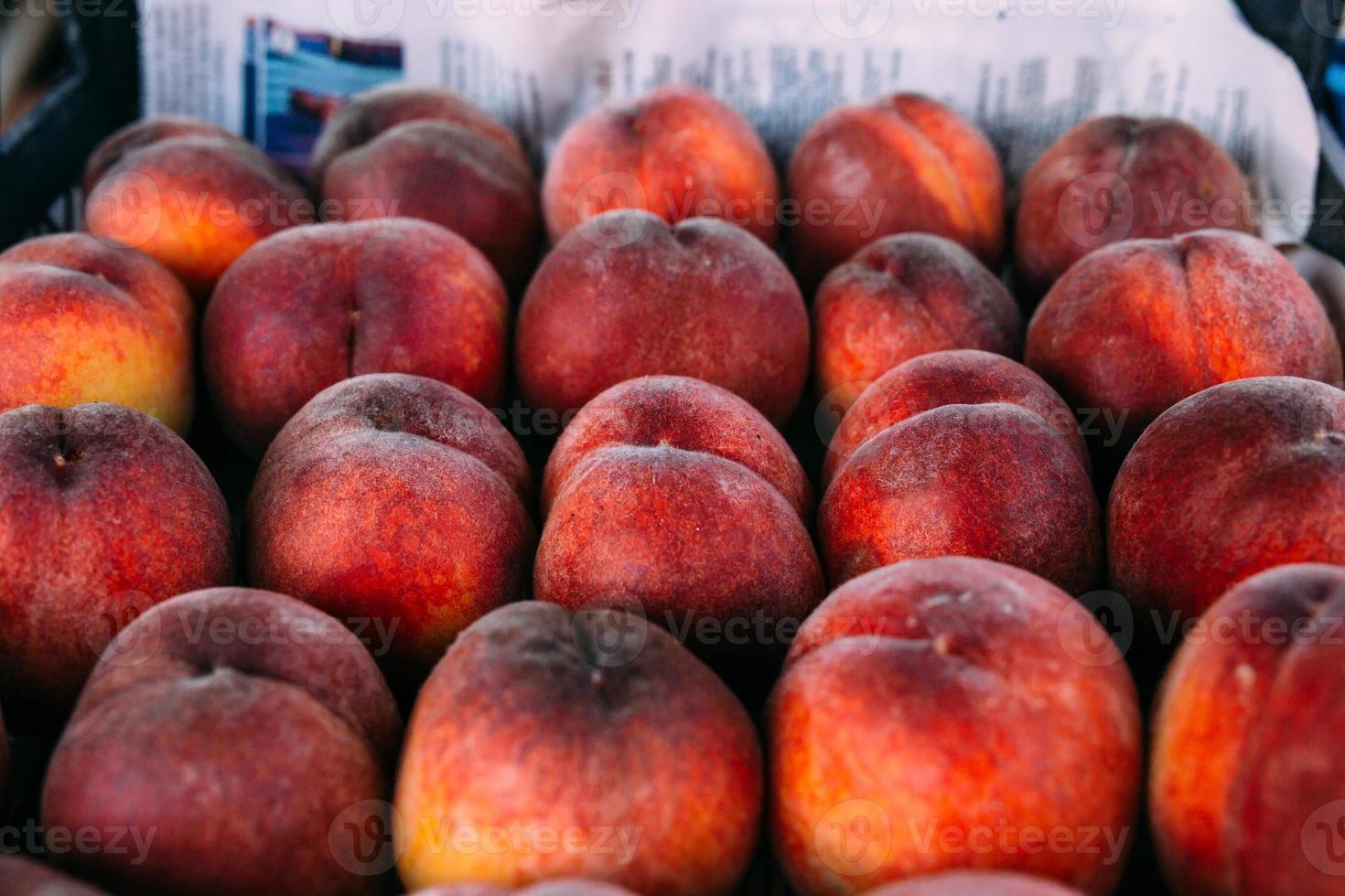 pêssegos vermelhos suculentos brilhantes na barraca do mercado de um fazendeiro foto