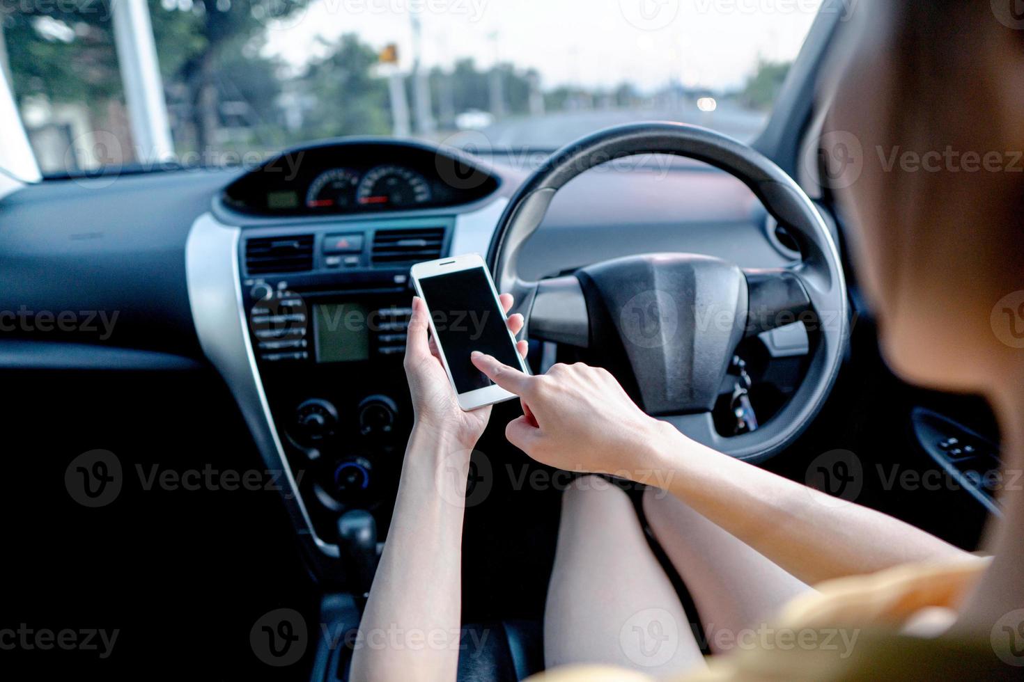 jovem mulher usando telefone inteligente enquanto dirige um carro foto