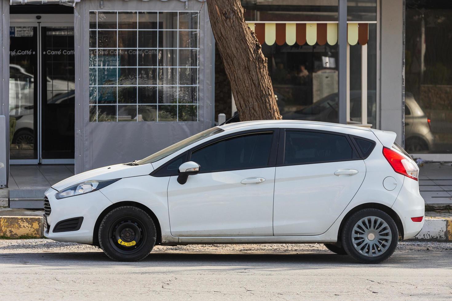 side turkey 18 de fevereiro de 2022 ford fiesta branco está estacionado na rua em um dia quente contra o pano de fundo de um edifício, parque, cerca, lojas foto