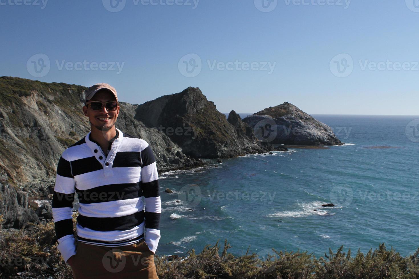 jovem com boné de beisebol ao lado da costa na califórnia foto