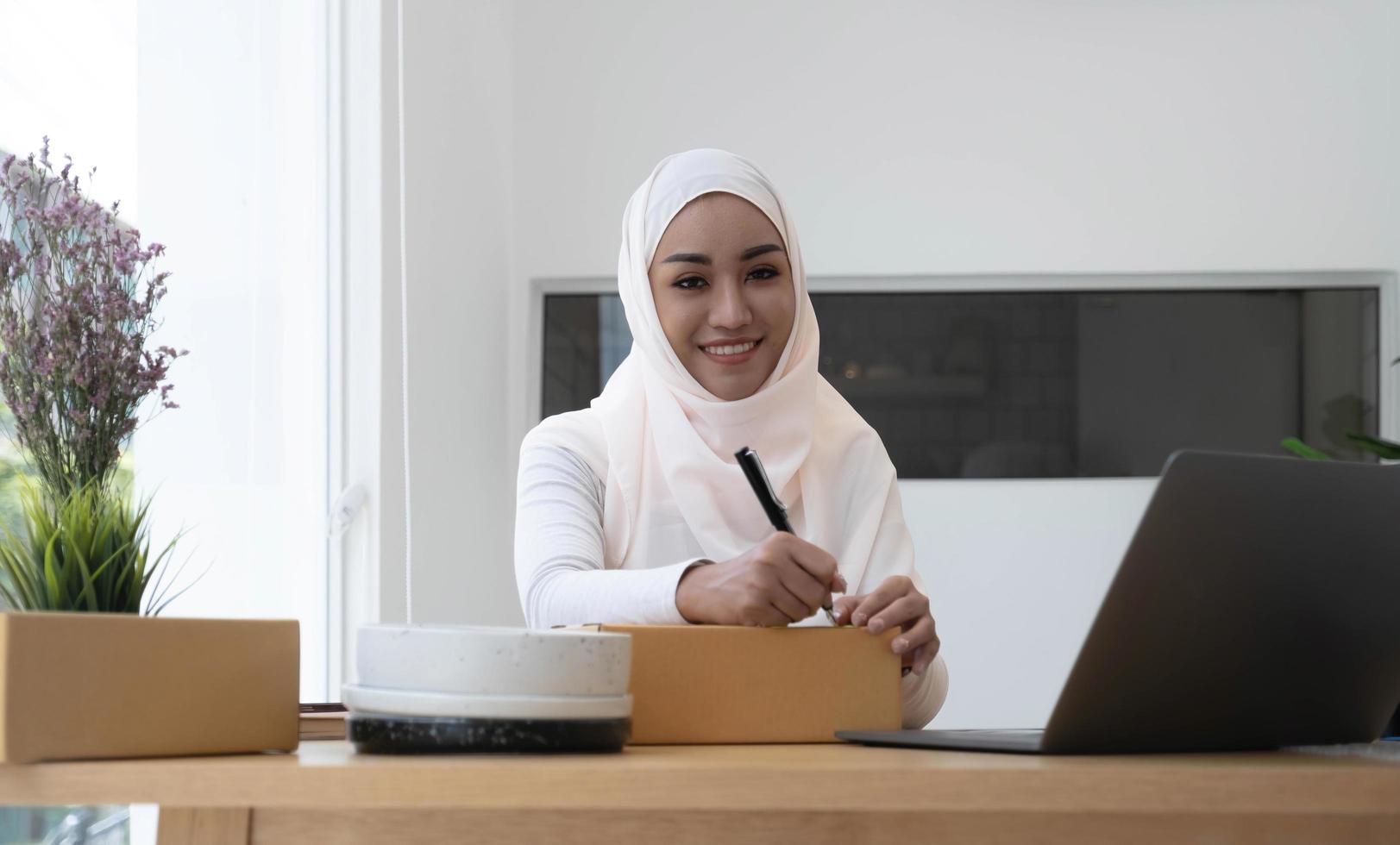 mulher de negócios muçulmana trabalhando no escritório, mulher de negócios muçulmana moderna, sme, pequenas empresas, comércio on-line e serviços de transporte. foto