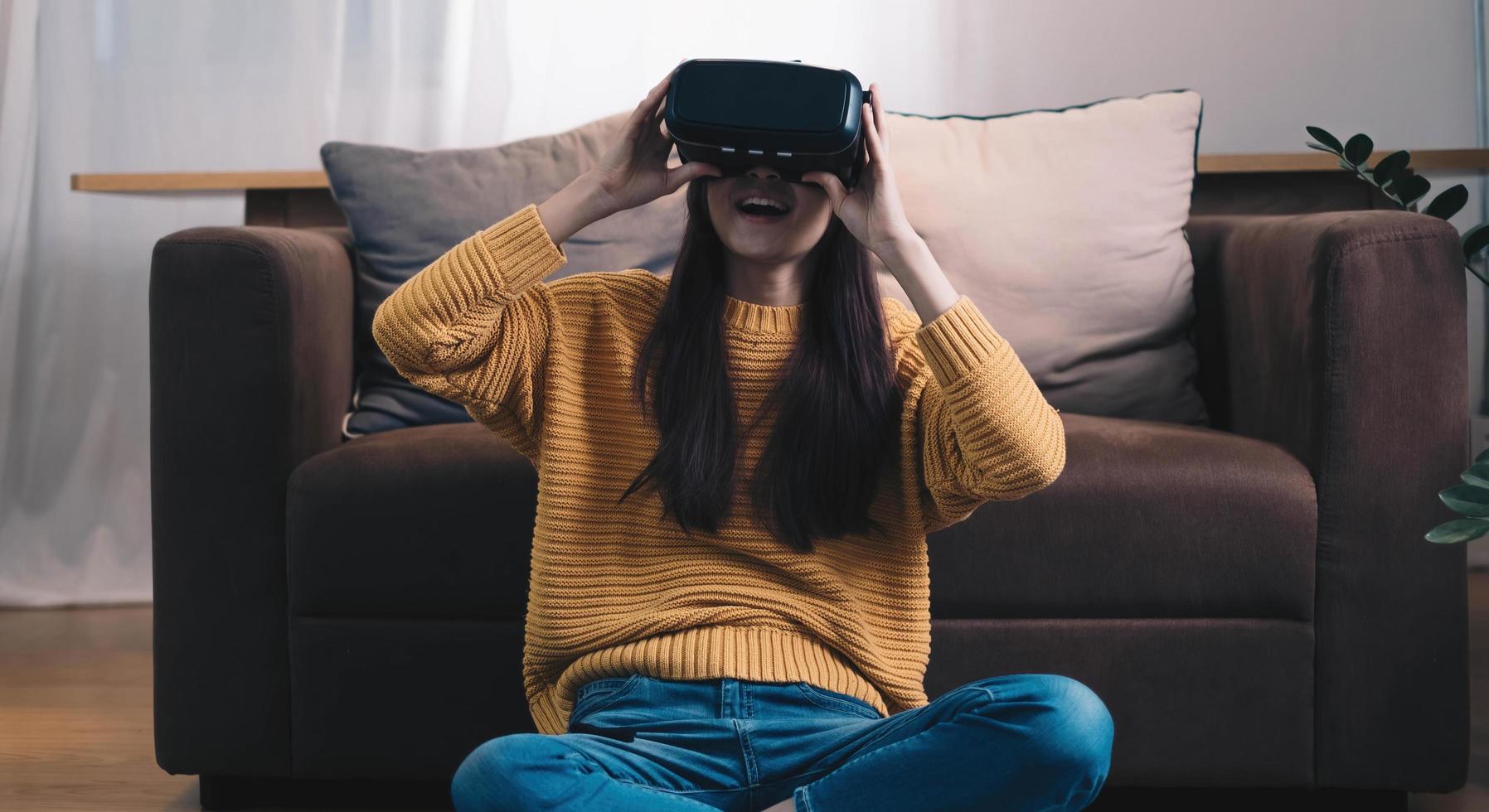 mulher asiática joga jogo vr para entreter em casa, mulher asiática alegre em casa de férias. mulher feliz jogando o conceito de tecnologia metaverse vr. foto