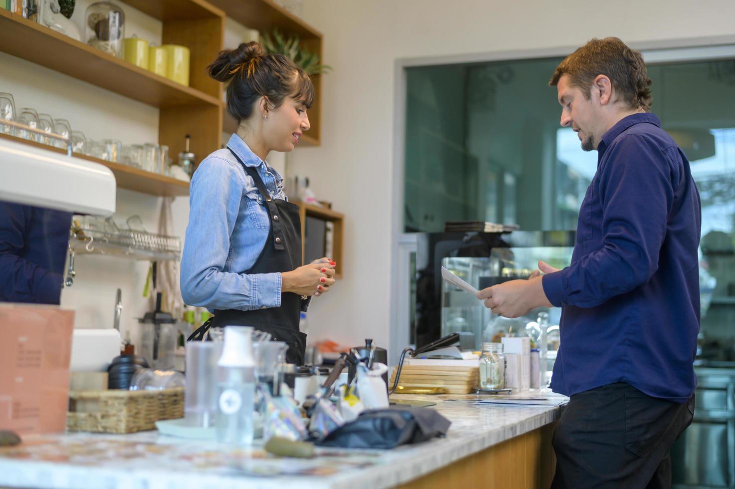 jovem barista de serviço com cliente na cafeteria foto