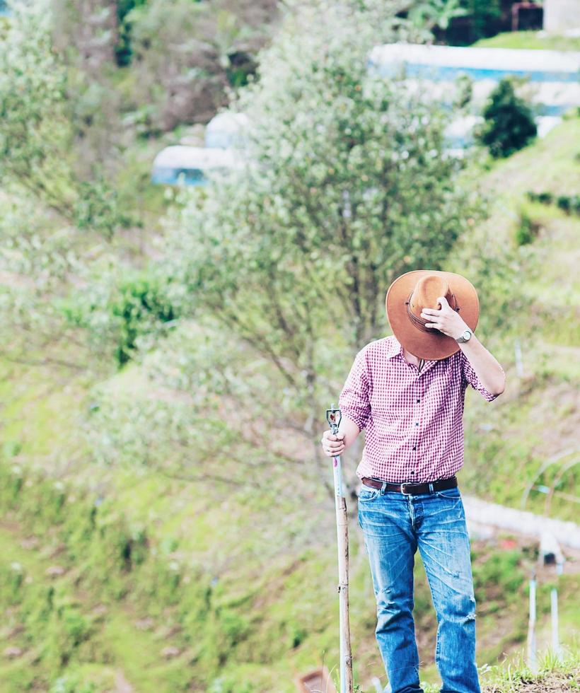 jovem agricultor em campo está trabalhando em sua terra agrícola de montanha está colocando chapéu chiang mai tailândia - pessoas no conceito de negócios agrícolas locais foto