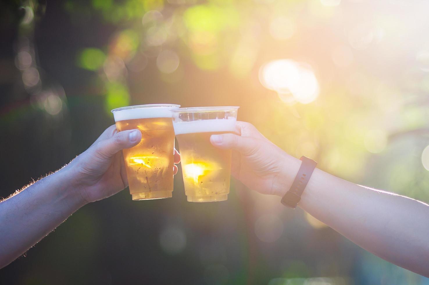 celebração cerveja comemora conceito - feche as mãos segurando copos de cerveja do grupo de pessoas em festa ao ar livre durante sua competição de vitória ou reunião de tarefa bem-sucedida foto