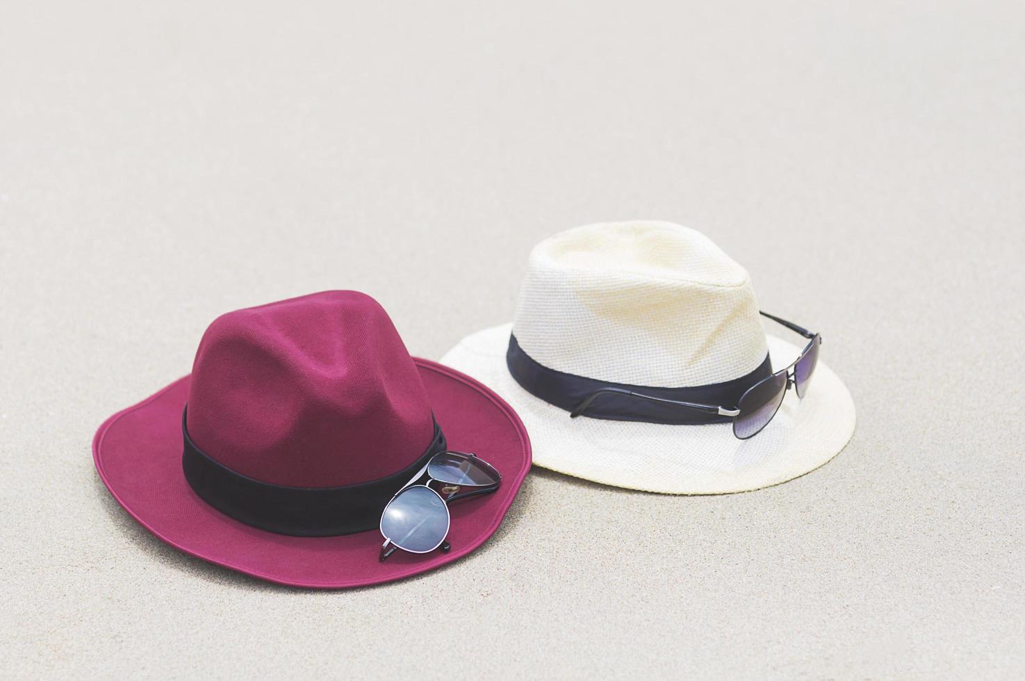 chapéu e óculos de sol na praia de areia fina em dia ensolarado foto