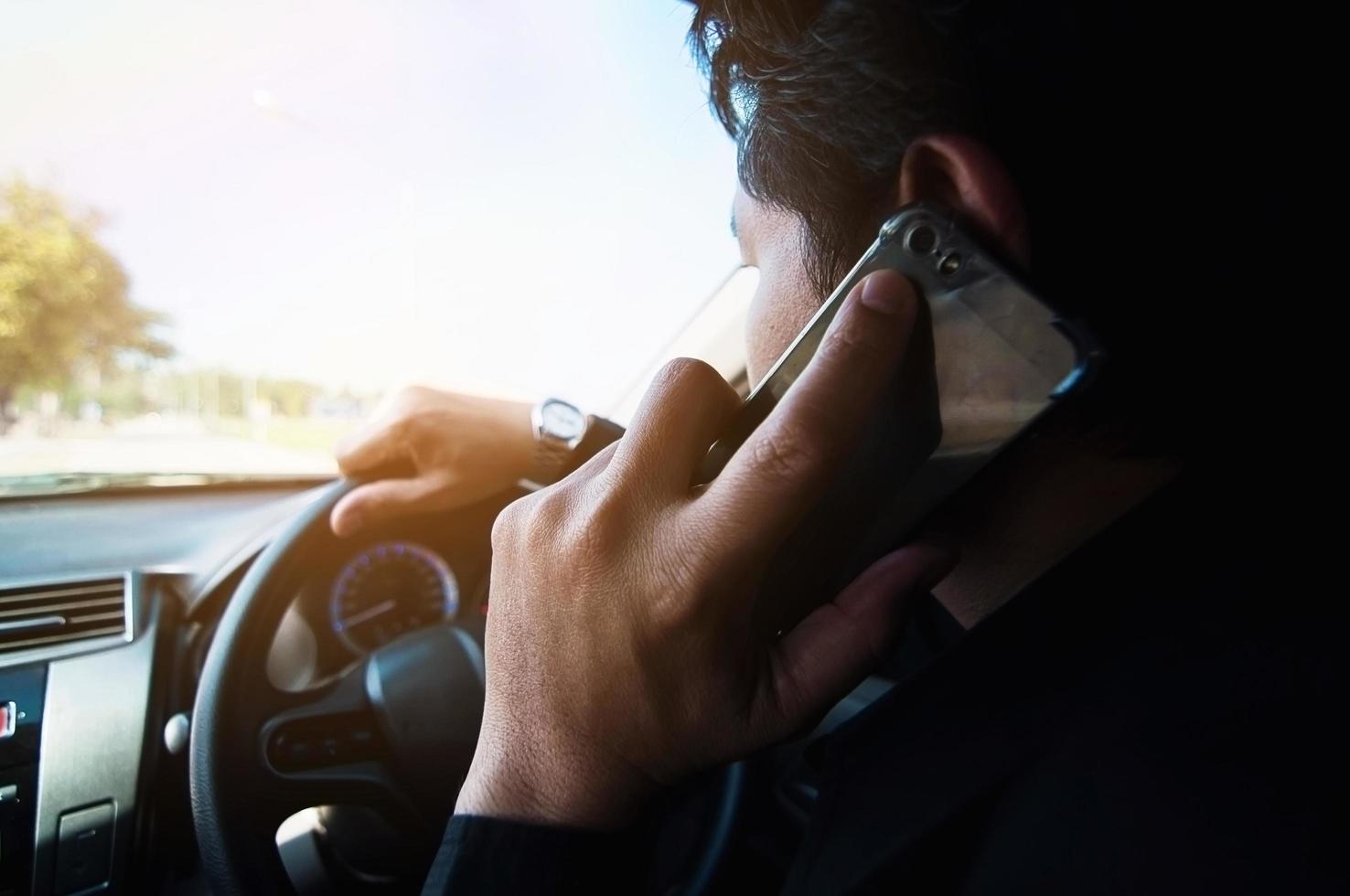 close-up de um homem dirigindo um carro perigosamente ao usar o telefone celular foto