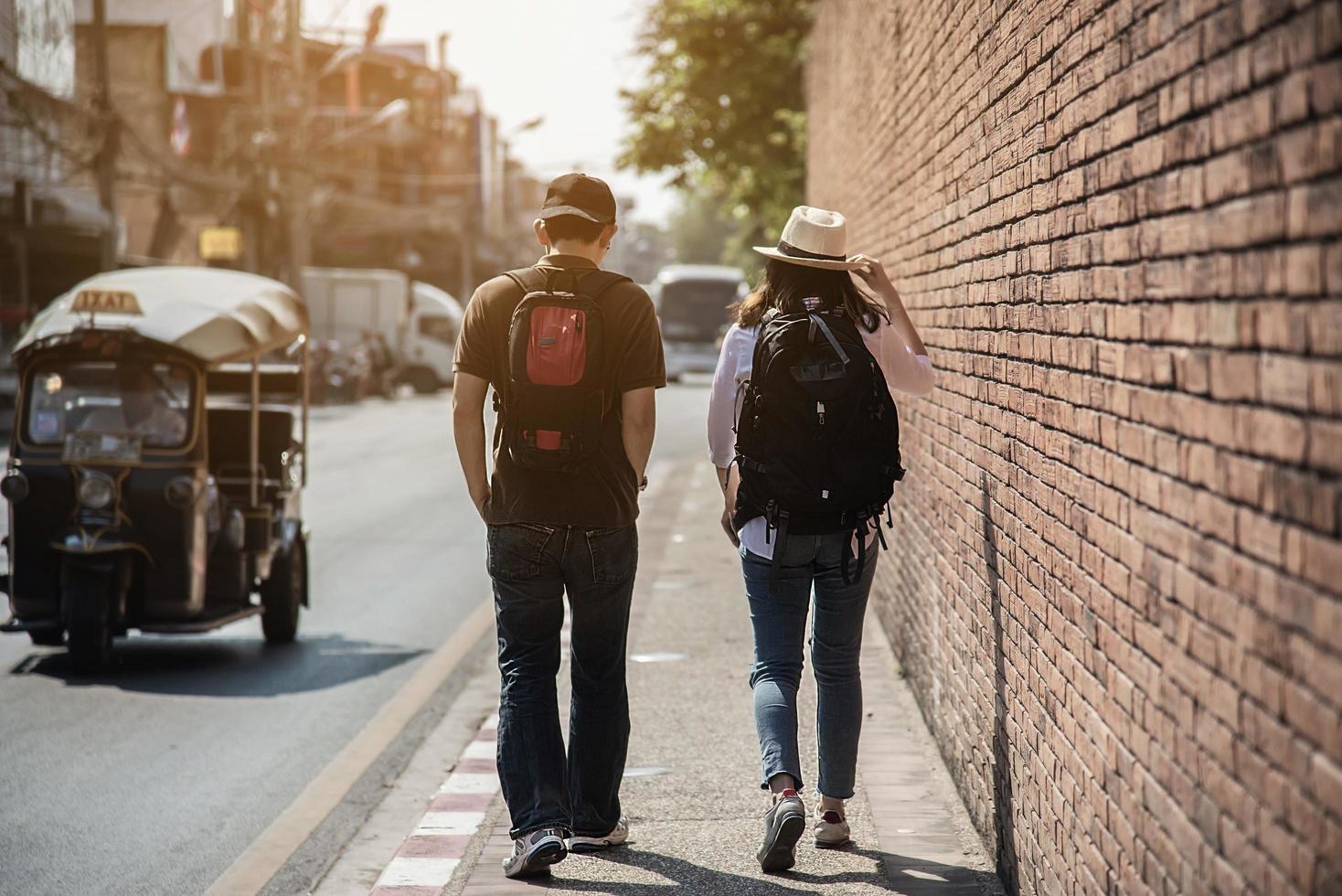 turista de casal de mochila asiática segurando o mapa da cidade atravessando a estrada - conceito de estilo de vida de férias de pessoas de viagem foto