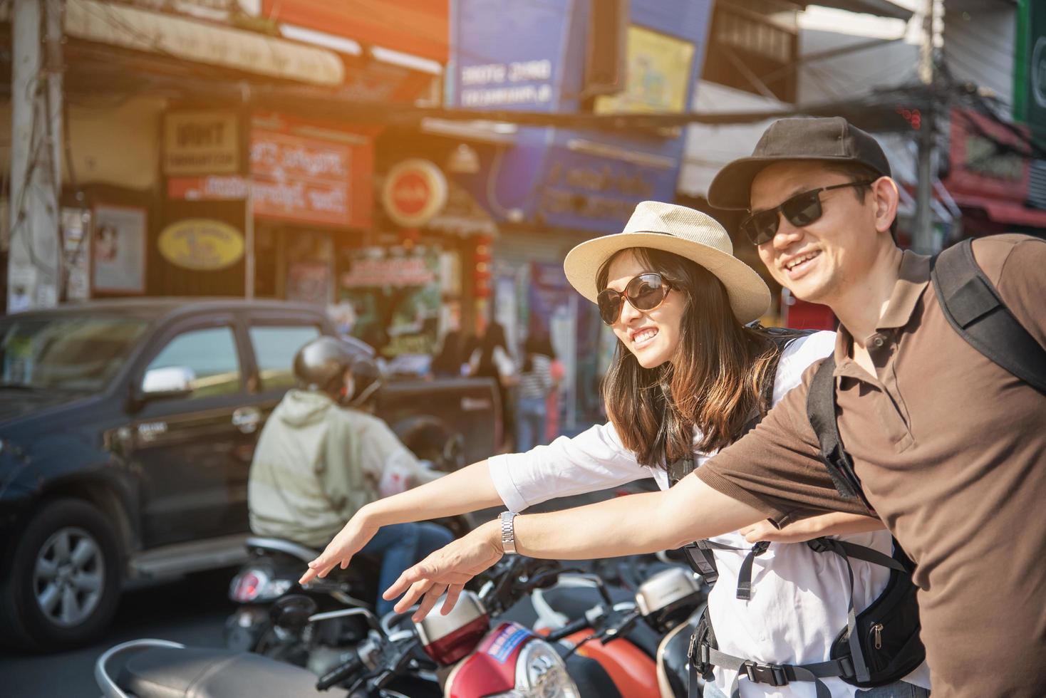 turista de casal de mochila asiática segurando o mapa da cidade atravessando a estrada - conceito de estilo de vida de férias de pessoas de viagem foto