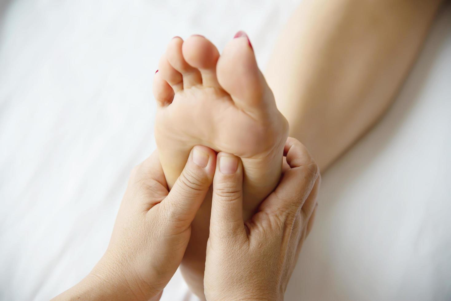 mulher recebendo serviço de massagem nos pés do massagista close-up na mão e no pé - relaxe no conceito de serviço de massagem terapêutica nos pés foto