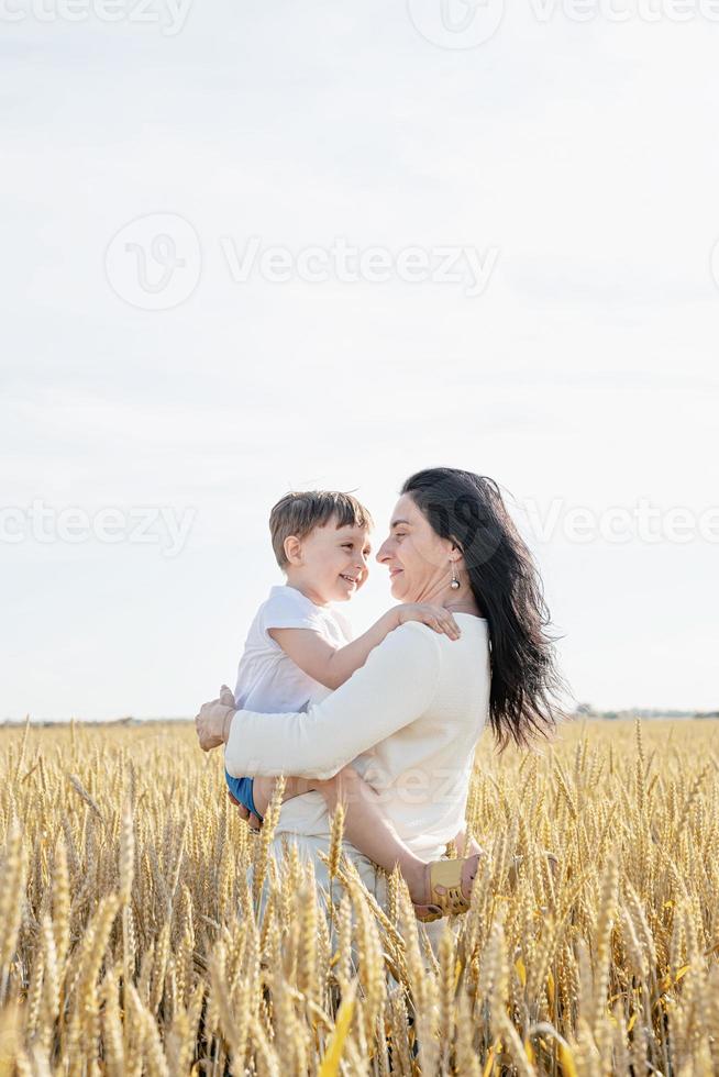 família feliz de mãe e criança caminhando no campo de trigo, retrato de família foto