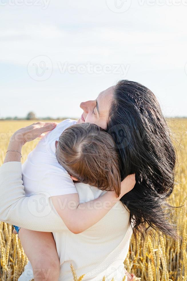 família feliz de mãe e criança caminhando no campo de trigo, retrato de família foto
