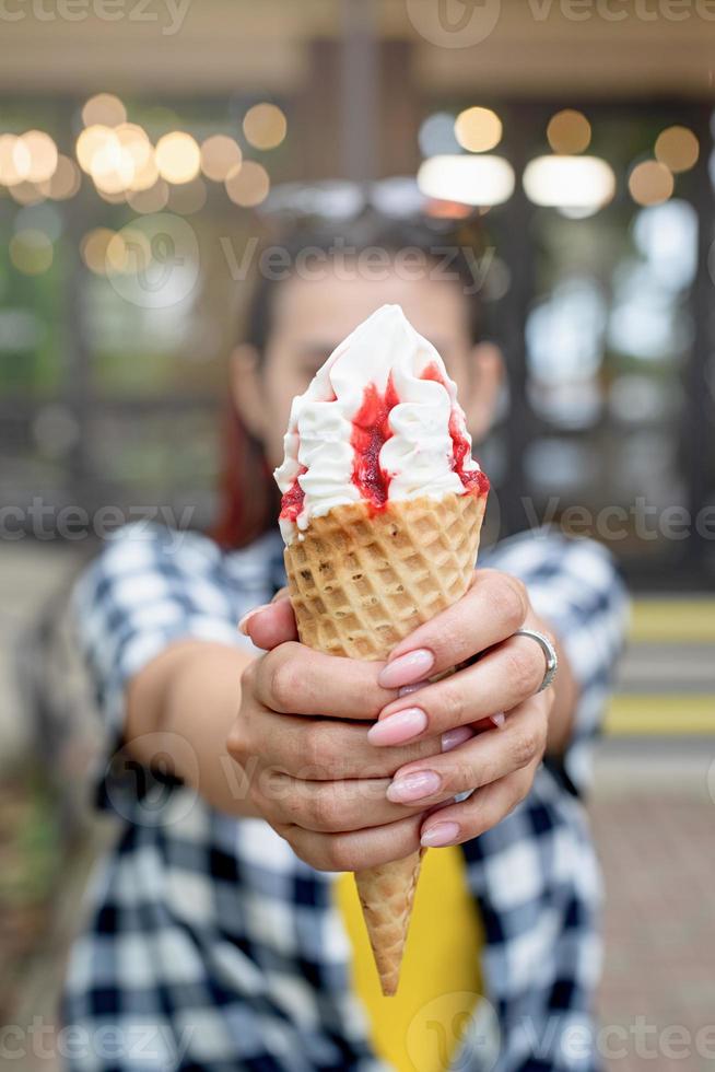 alegre mulher na moda com cabelo vermelho comendo sorvete na rua foto