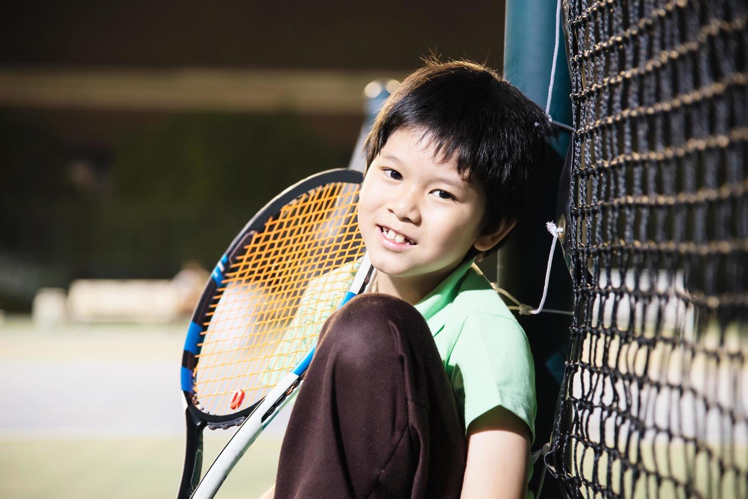 menino feliz na quadra de tênis durante seu tempo de prática esportiva - esporte de tênis com conceito de pessoas foto