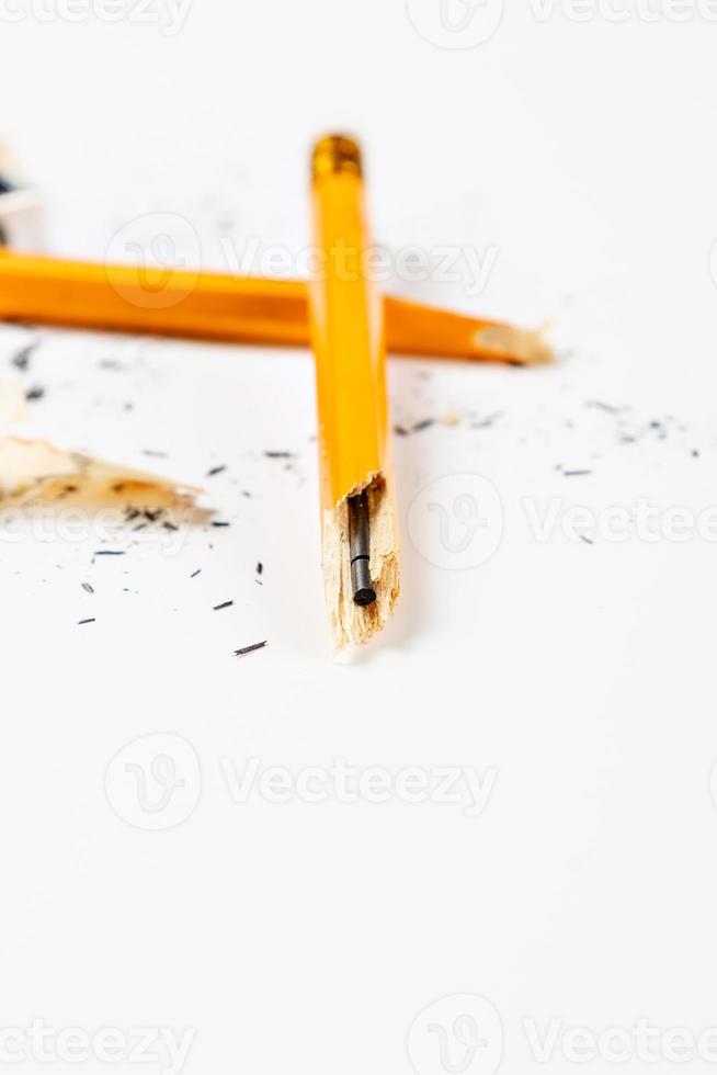 lápis quebrado com aparas em fundo branco. imagem vertical. foto