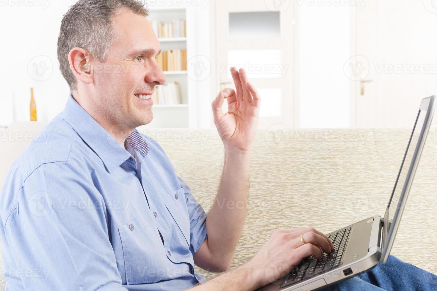 homem surdo, usando a linguagem de sinais com laptop foto