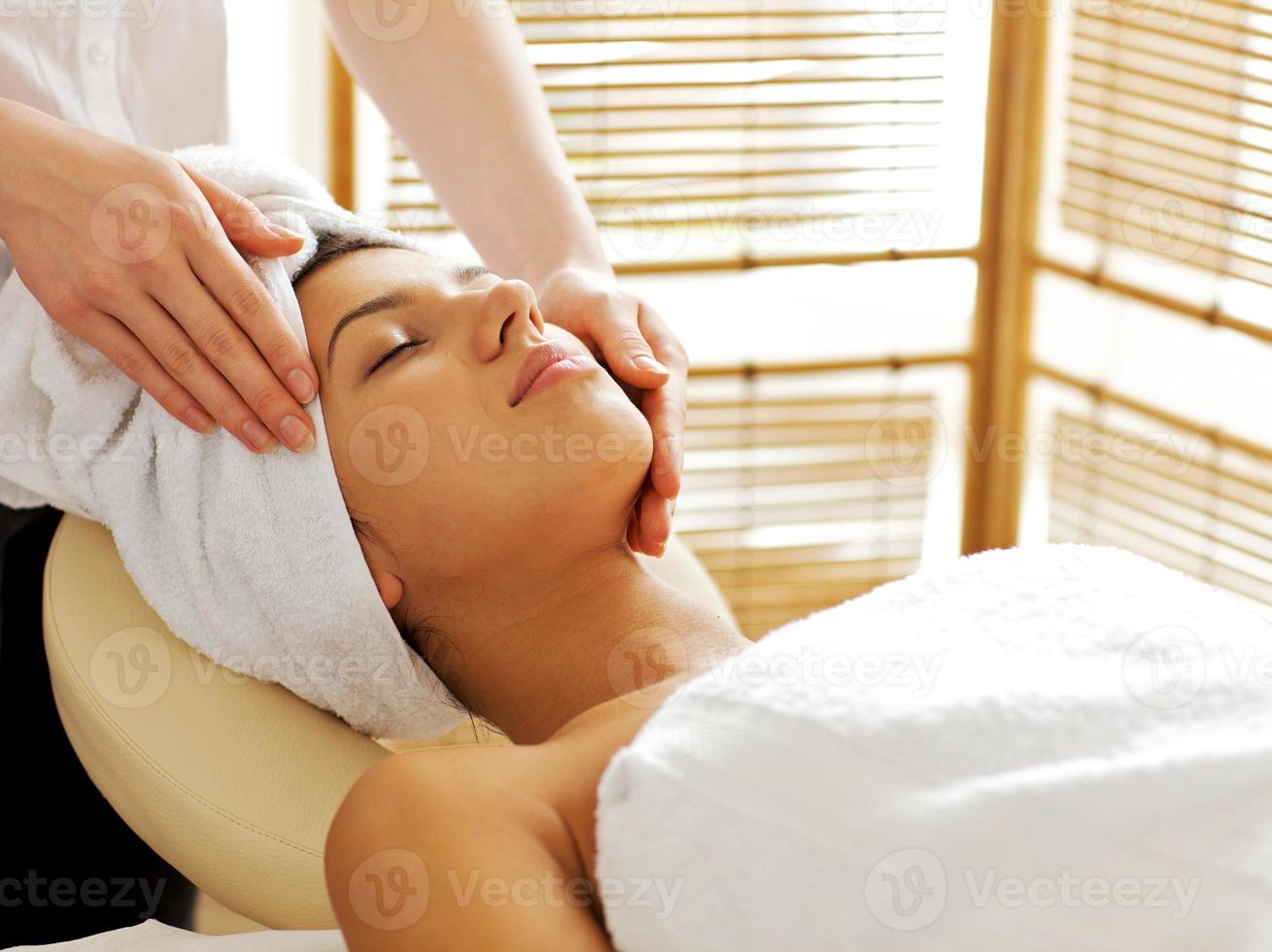 jovem mulher recebendo massagem facial, olhos fechados foto
