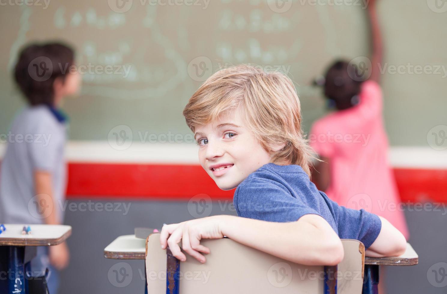 sala de aula elementar multi étnica. garoto olhando para a câmera enquanto c foto