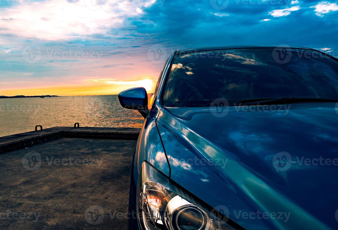 carro suv compacto azul com esporte e design moderno estacionado na estrada de concreto à beira-mar ao pôr do sol à noite. conceito de tecnologia de carro híbrido e elétrico. vaga de estacionamento. indústria automobilística. foto