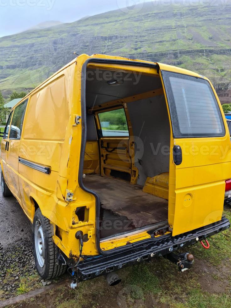 um carro de transporte abandonado amarelo com uma porta faltando na parte de trás. foto