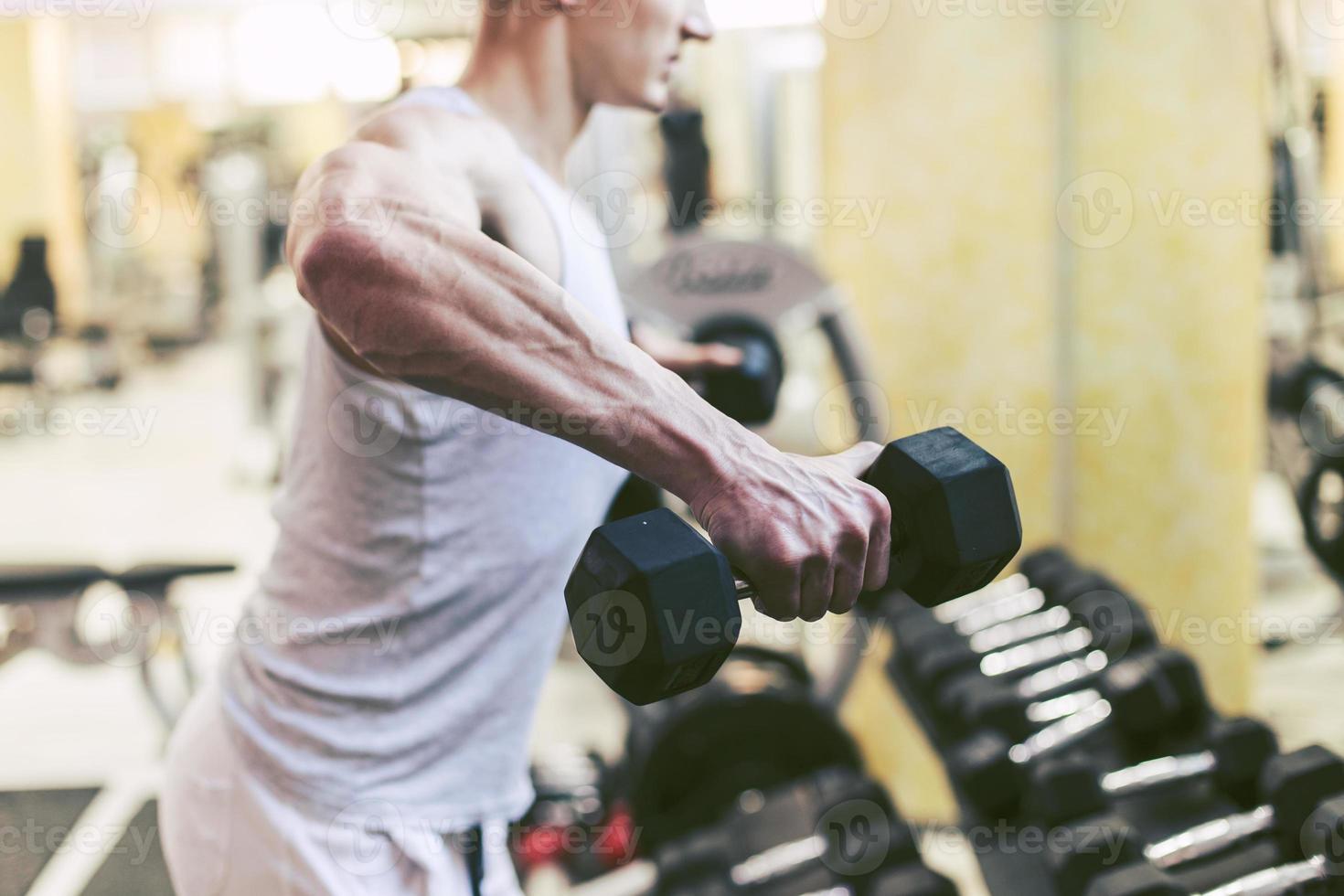 fisiculturista muscular fazendo exercícios com halteres no ginásio foto