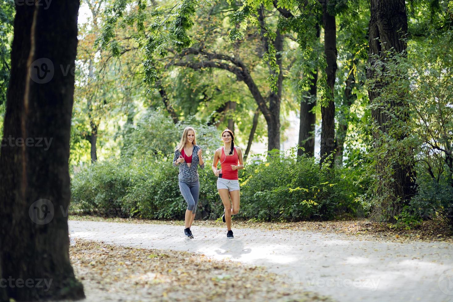 duas belas mulheres correndo no parque foto