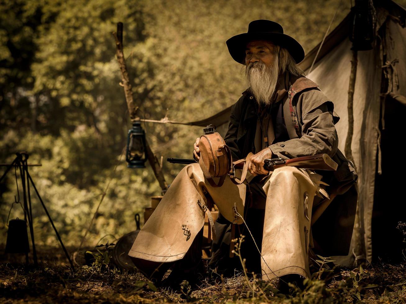 um cowboy sênior sentou-se com uma arma para proteger a segurança do acampamento na área oeste foto