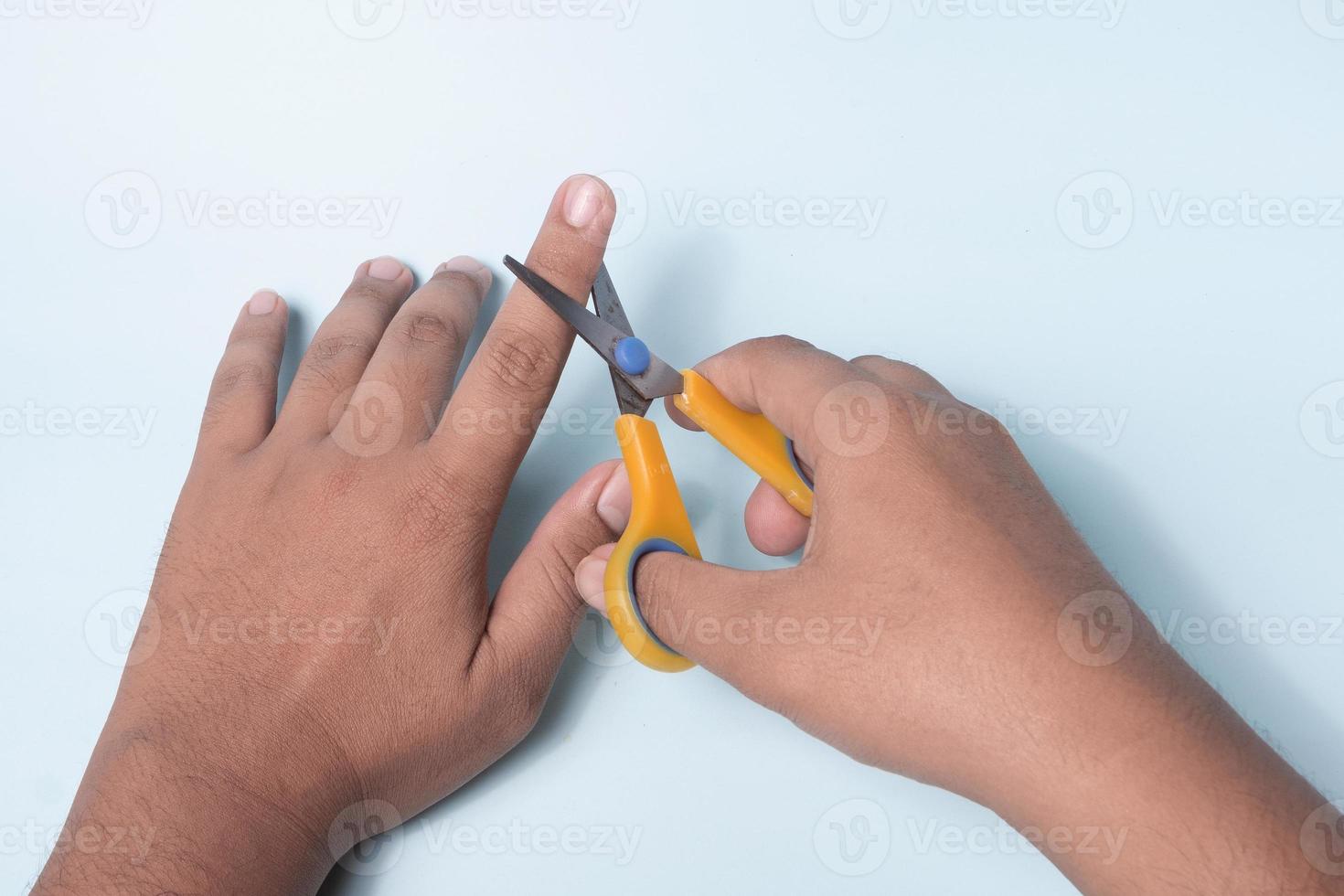 a mão de um homem está tentando cortar um dedo usando uma tesoura foto