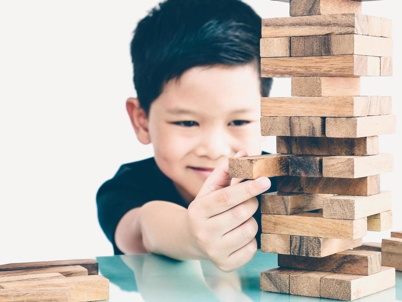 tom vintage de criança asiática está jogando jogo de torre de blocos de madeira para praticar habilidade física e mental. a foto está focada é as mãos.