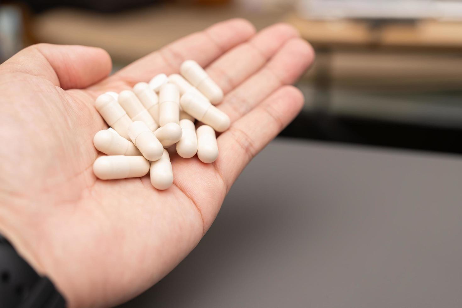 mão de um homem com pílulas brancas na palma da mão. conceito médico de tratamento de doenças com drogas. foto