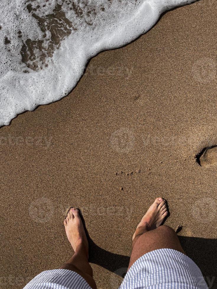 pés pisando na praia de areia amarela. foto
