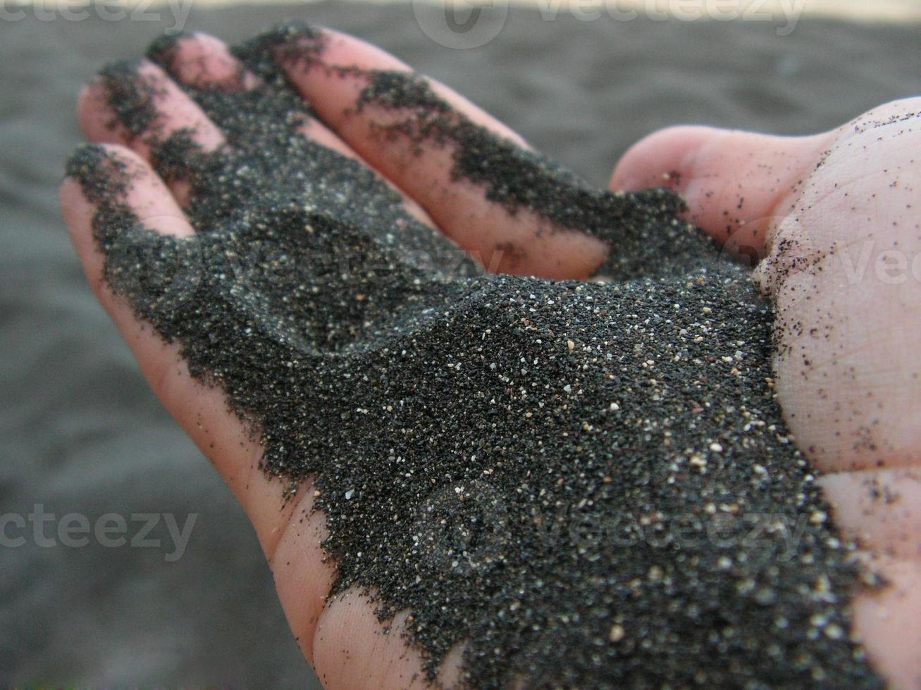 areia preta em uma mão foto