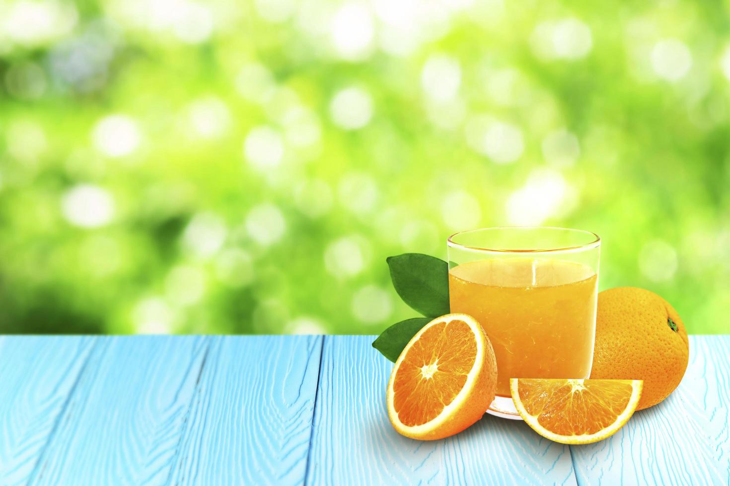 copo de suco de laranja com fatias de laranja frescas sobre fundo azul de madeira. foto