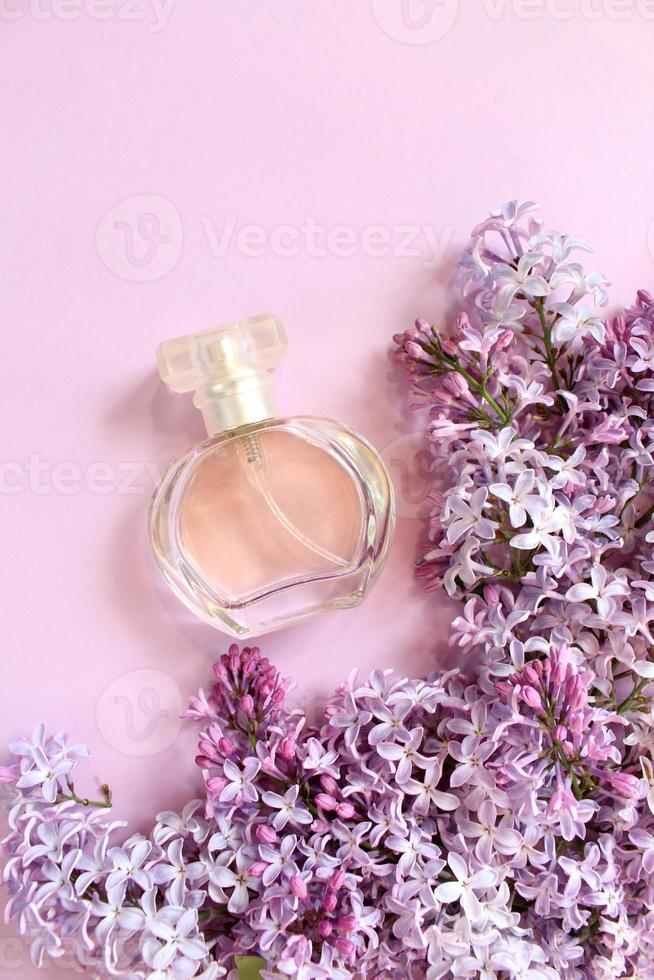 frasco de perfume lilás com spray de flores lilás no fundo. composição floral criativa. fechar-se. perfumaria natural e conceito de aroma floral. perfumado de primavera fresca foto