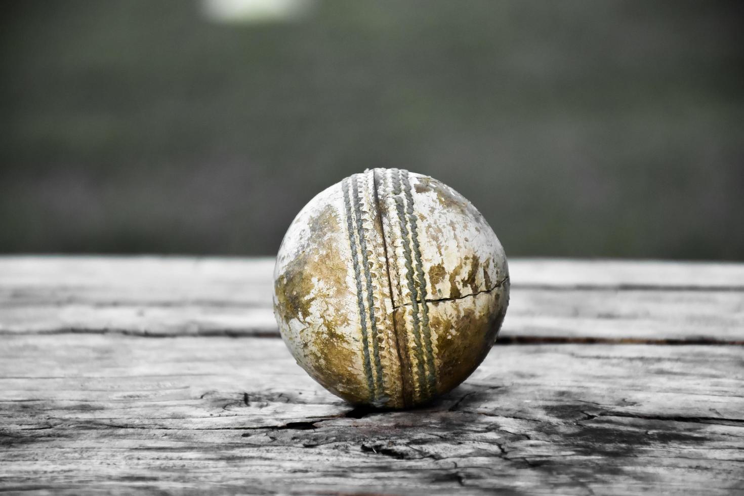 equipamentos de esporte de críquete de treinamento antigo no chão escuro, bola de couro, postigos, capacete e taco de madeira, foco suave e seletivo, amantes do esporte de críquete tradicional em todo o conceito do mundo. foto