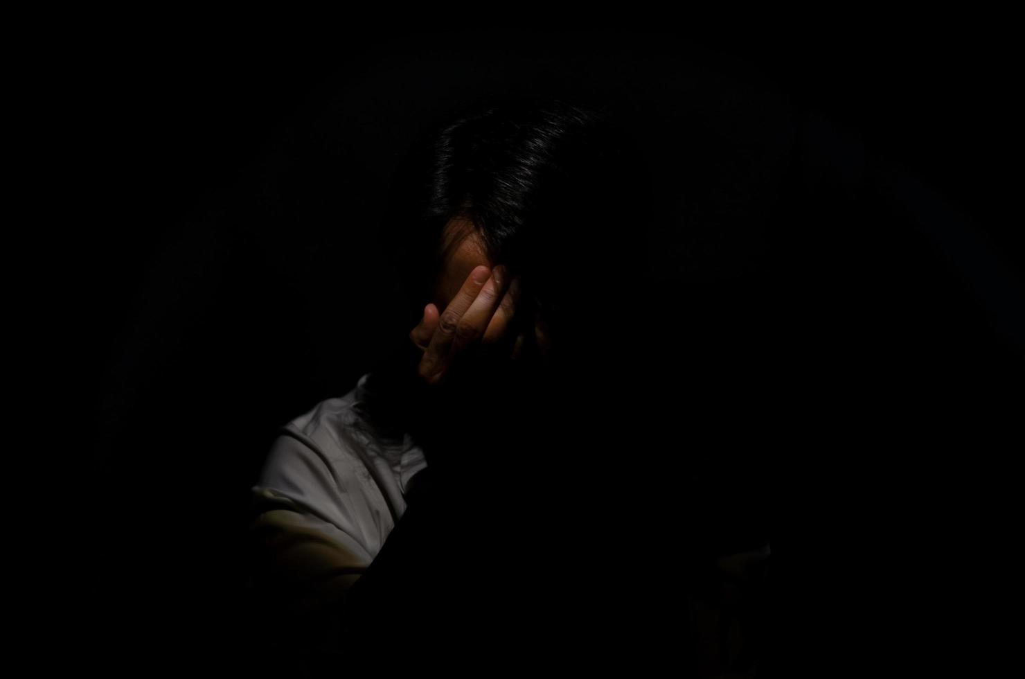 homem deprimido miserável asiático sentado sozinho no fundo escuro. depressão e conceito de saúde mental. foto