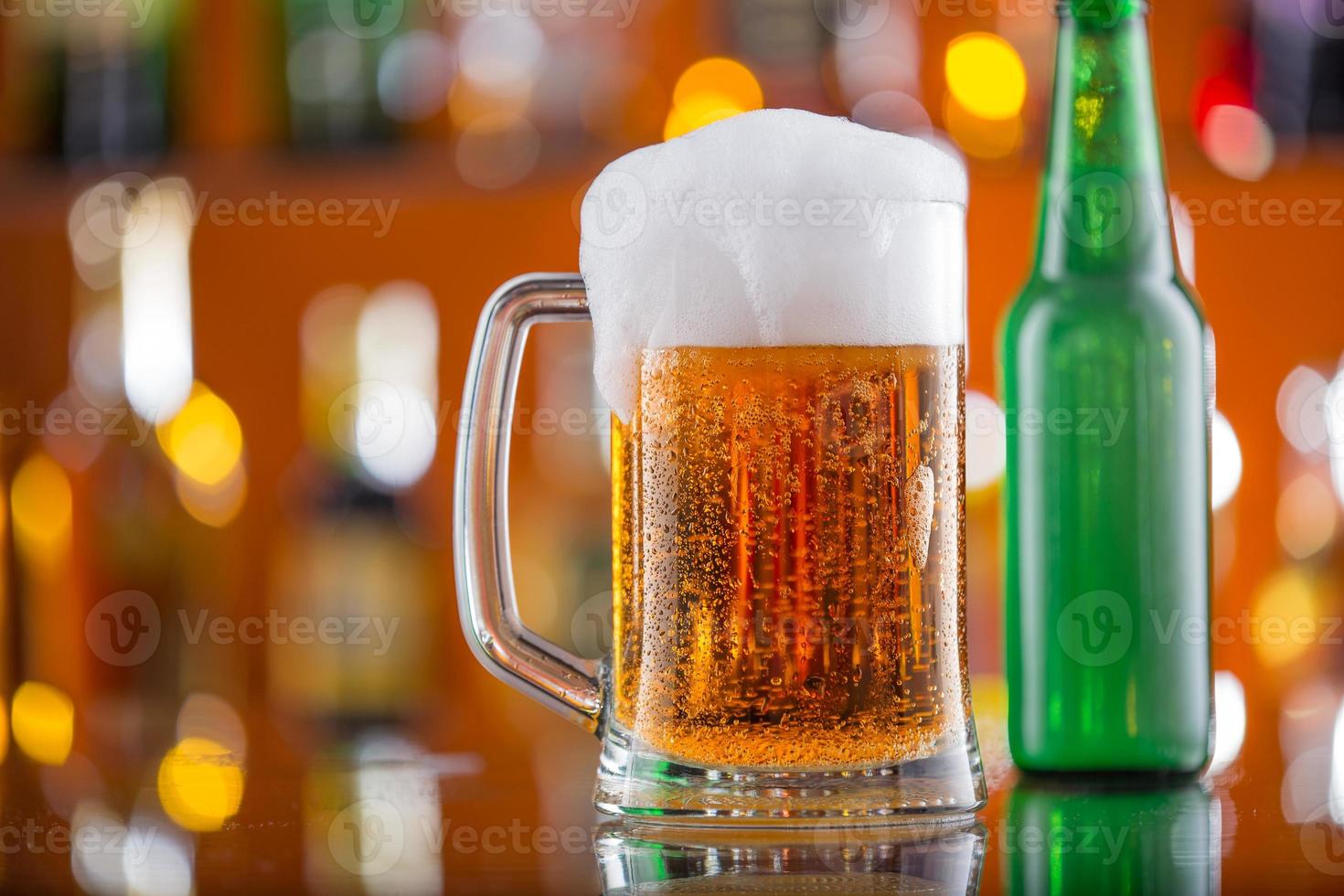garrafa de cerveja com copo na mesa de bar foto