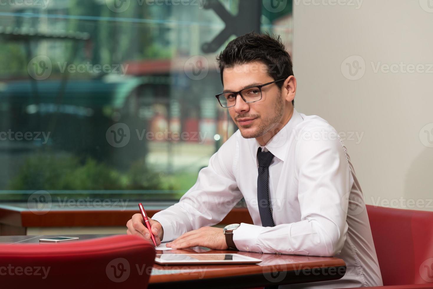 empresário sentado na mesa do escritório, assinando um contrato foto