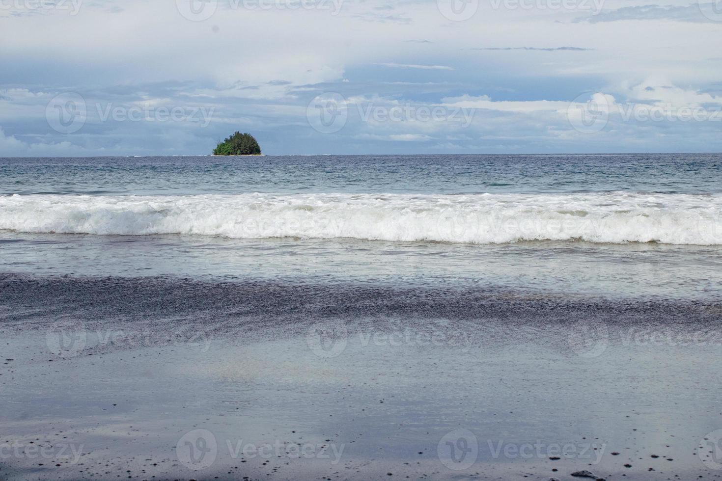 uma pequena ilha no oceano com ondas do mar foto