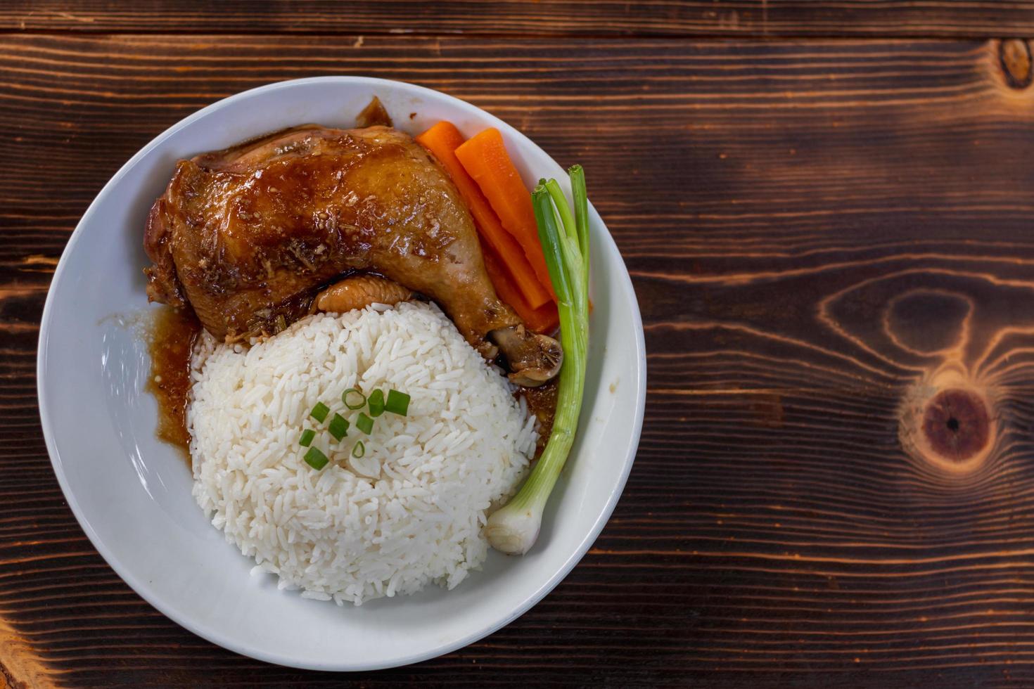 coxas de frango assadas e coxinhas são servidas com arroz de jasmim e legumes frescos em um prato branco. as coxas de frango assadas em molho doce e delicioso são servidas com arroz cozido no vapor quente em um prato. foto