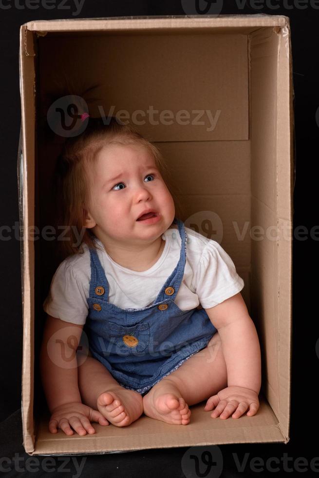 menina feliz sentada em uma caixa de papelão e se divertindo foto