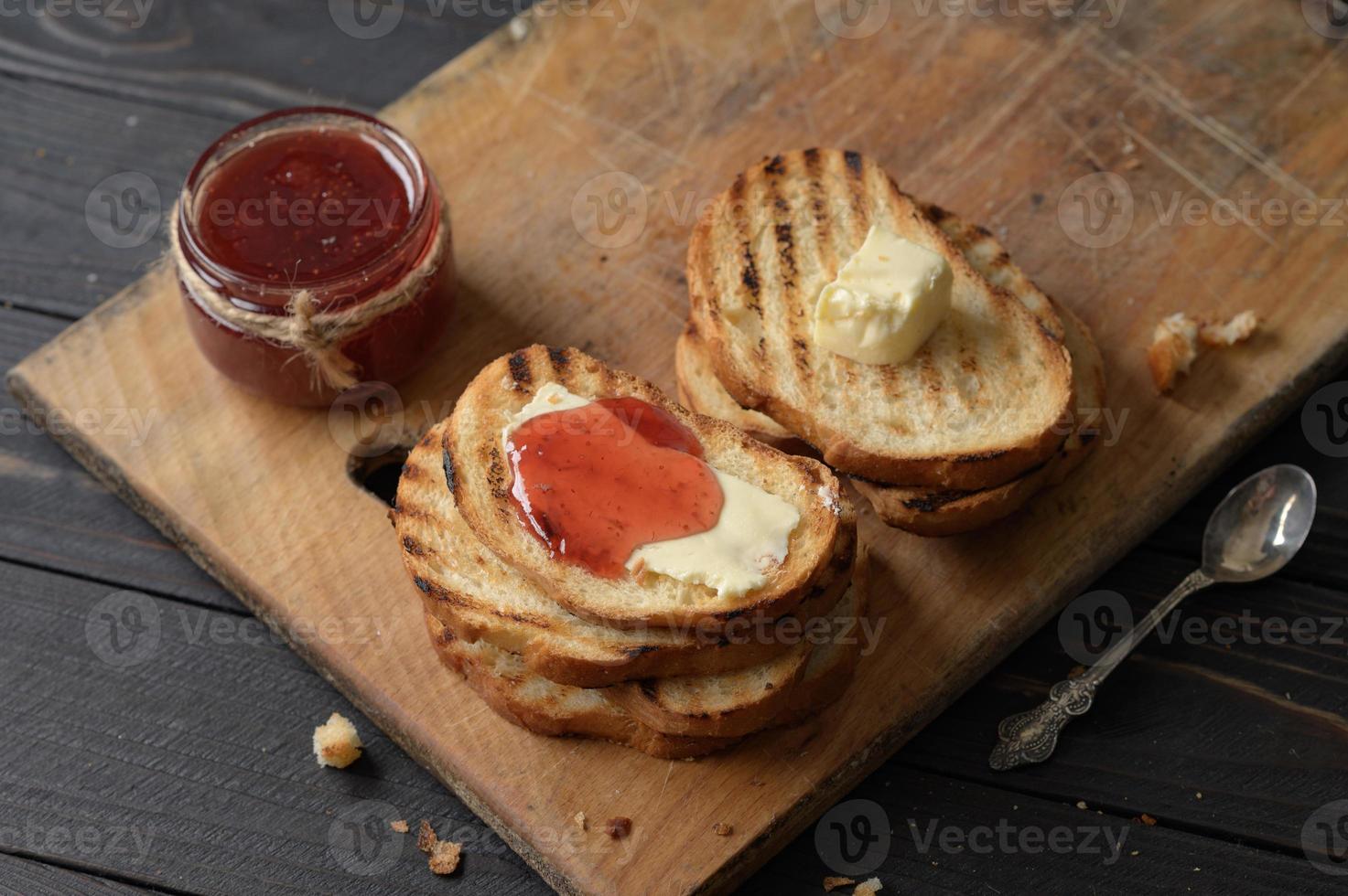 torradas de pão com geléia de morango caseira e na mesa rústica com manteiga no café da manhã ou brunch. foto