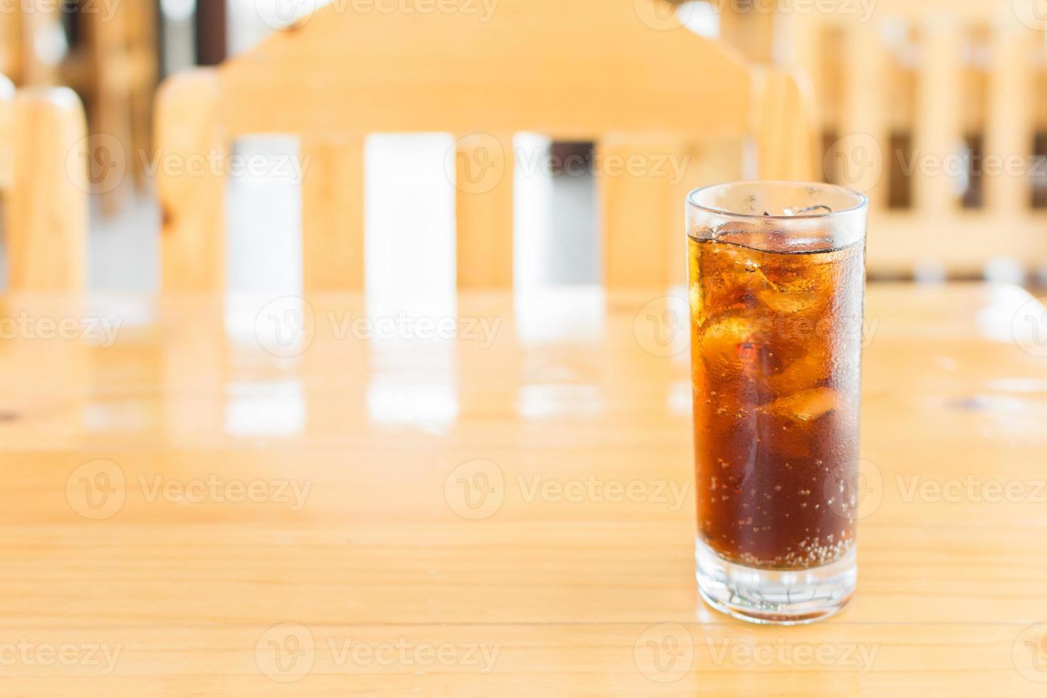 refrigerante de cola com gelo em vidro na mesa de madeira foto