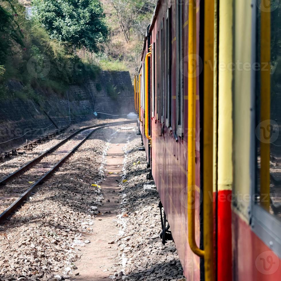 trem de brinquedo movendo-se nas encostas das montanhas, bela vista, uma montanha lateral, um vale lateral movendo-se na ferrovia para a colina, entre a floresta natural verde. trem de brinquedo de kalka para shimla na índia foto