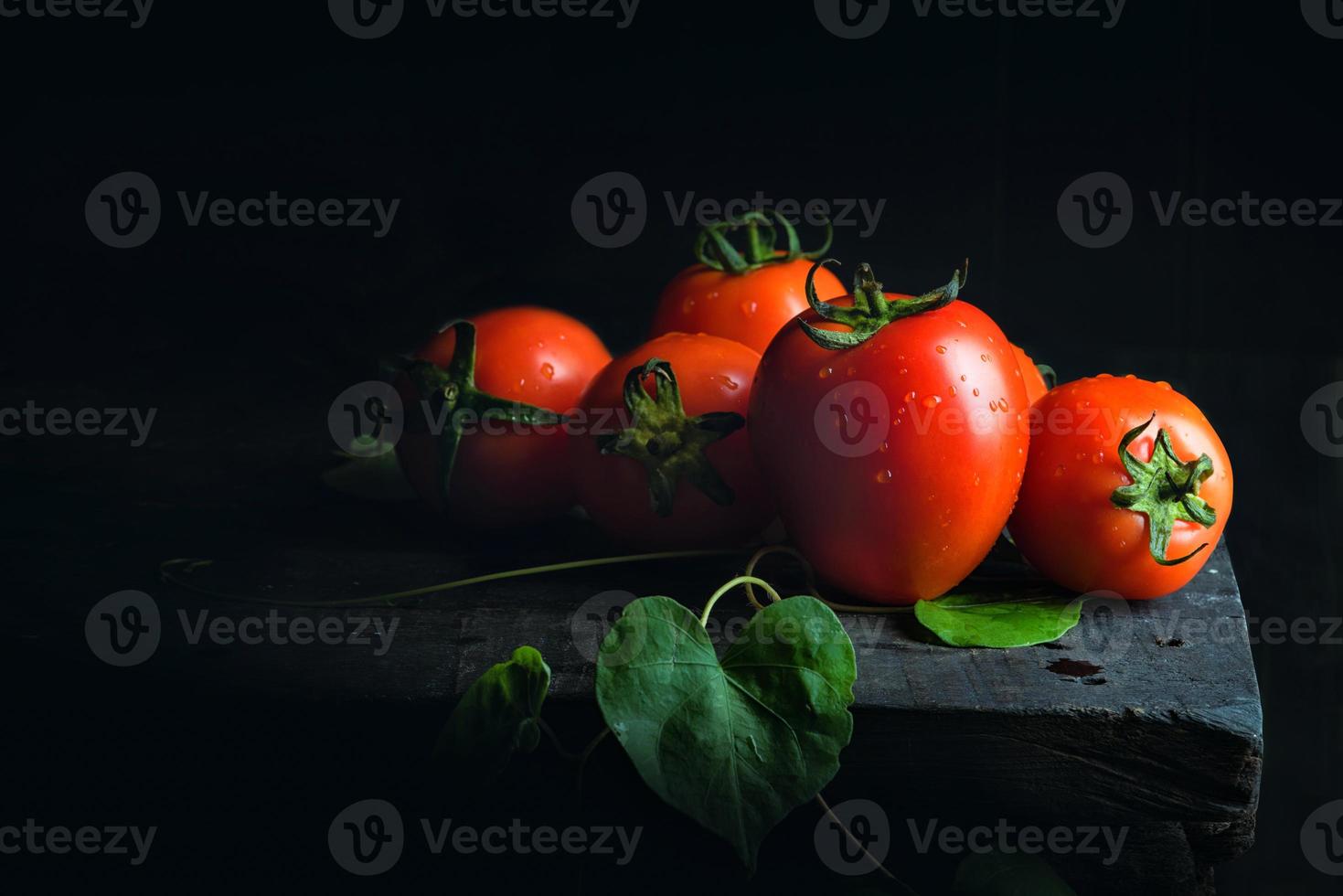 tomate vegetal e folha verde no velho piso de madeira escuro preto antigo foto