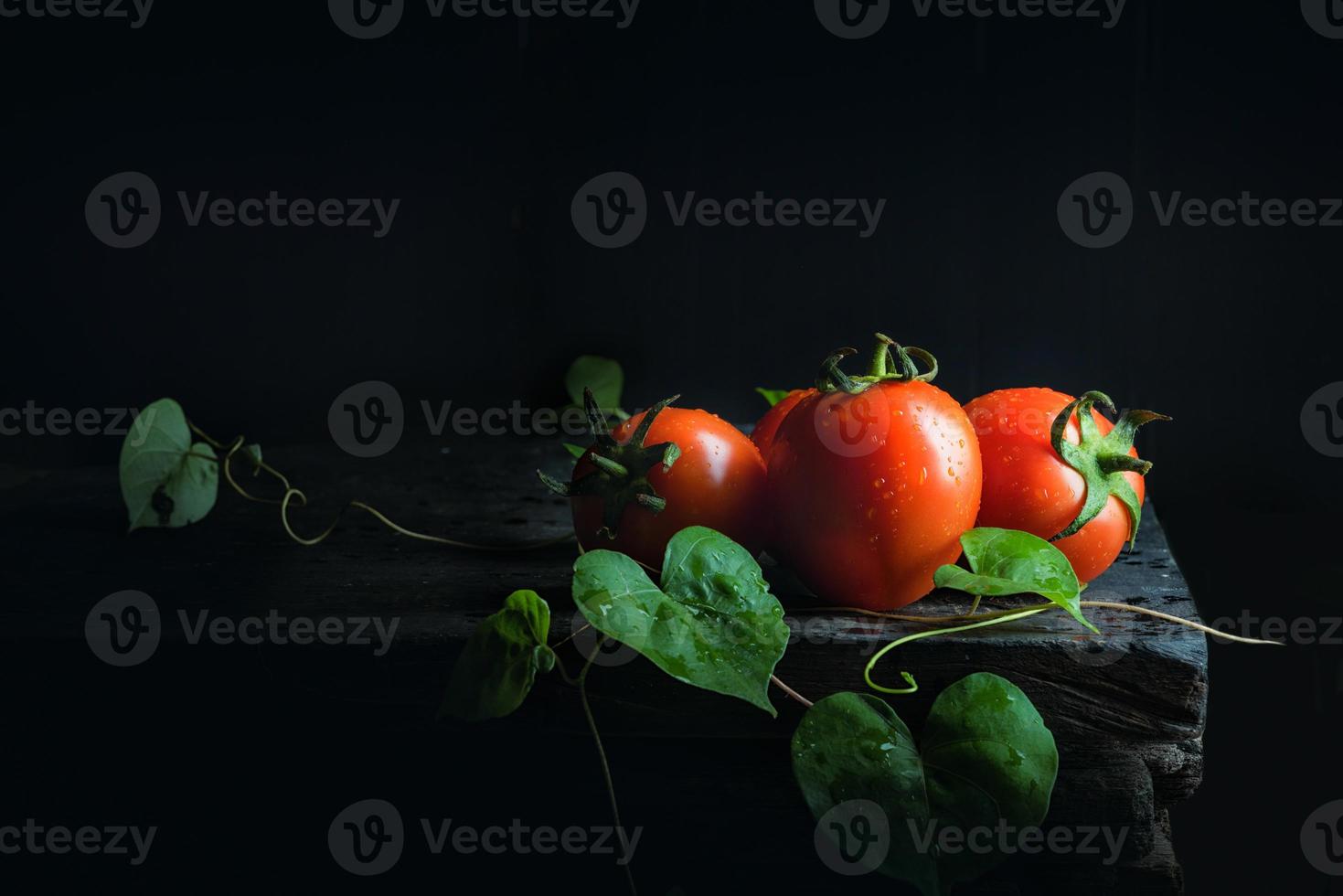 tomate vegetal e folha verde no velho piso de madeira escuro preto antigo foto